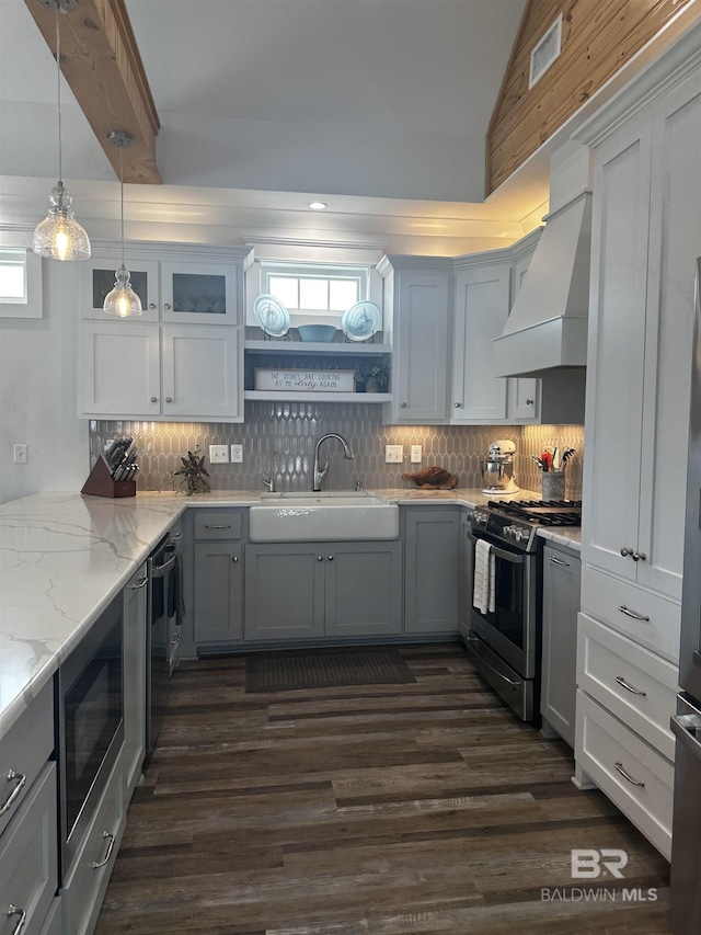 kitchen with custom exhaust hood, a sink, built in microwave, stainless steel range with gas stovetop, and dark wood-style floors