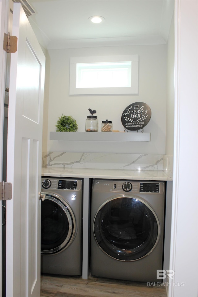 washroom featuring washing machine and dryer, wood finished floors, and laundry area