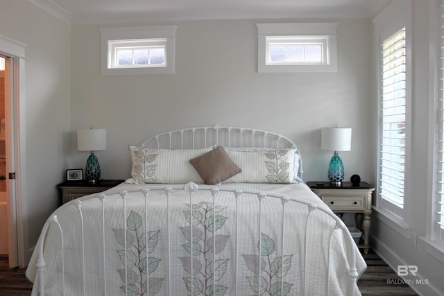 bedroom featuring baseboards, wood finished floors, and multiple windows