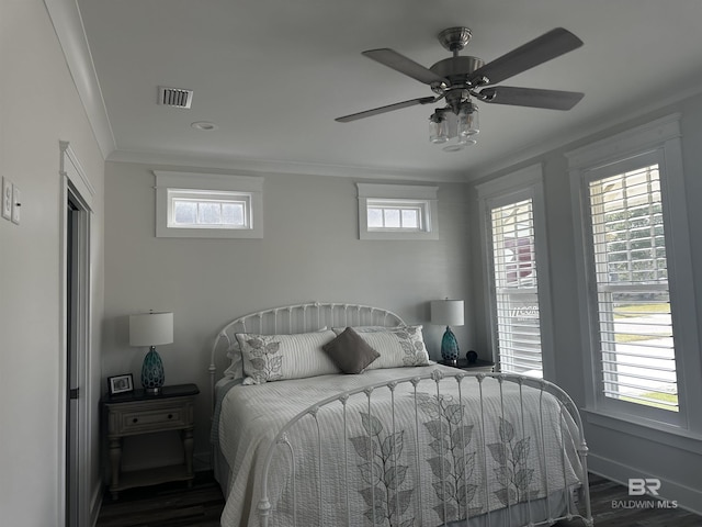 bedroom with wood finished floors, ornamental molding, and multiple windows