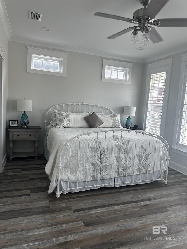 bedroom featuring multiple windows, wood finished floors, visible vents, and crown molding