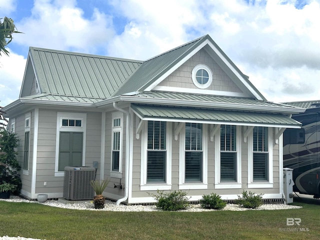 view of side of property featuring a standing seam roof, cooling unit, and metal roof