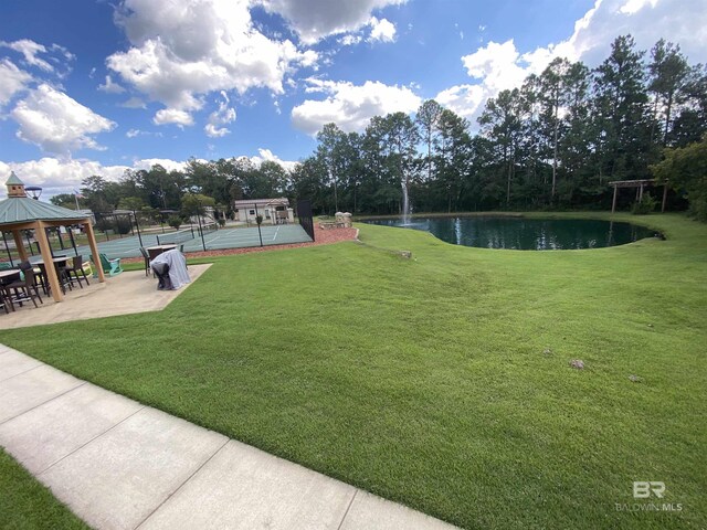 view of yard with fence, a gazebo, a water view, and a tennis court