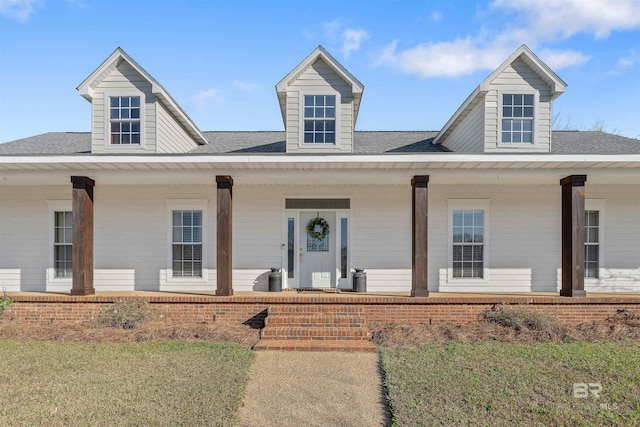 cape cod home with a front yard and a porch