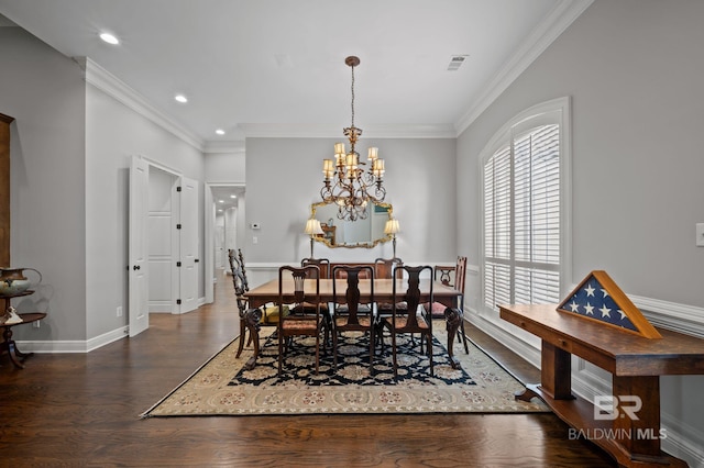 dining space featuring an inviting chandelier, ornamental molding, visible vents, wood finished floors, and baseboards