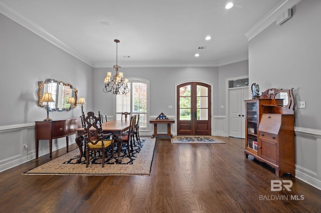 dining area featuring ornamental molding, a wainscoted wall, a notable chandelier, and wood finished floors