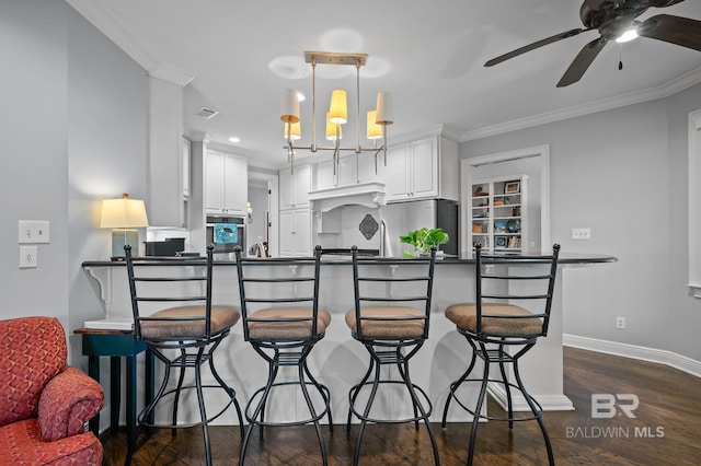 kitchen with baseboards, ornamental molding, dark countertops, freestanding refrigerator, and dark wood finished floors