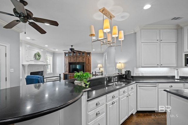 kitchen with crown molding, ceiling fan with notable chandelier, dark countertops, and visible vents