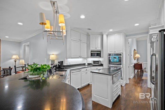 kitchen with crown molding, white cabinets, dark countertops, a sink, and stainless steel appliances