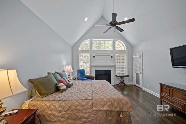 bedroom with baseboards, ceiling fan, dark wood finished floors, high vaulted ceiling, and a glass covered fireplace
