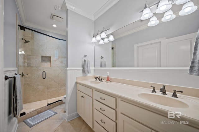 full bathroom featuring crown molding, toilet, a sink, a stall shower, and double vanity