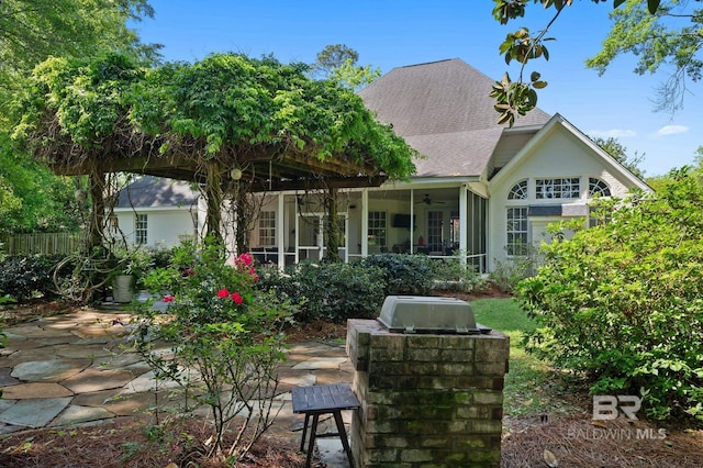 rear view of house featuring a patio area, a sunroom, a ceiling fan, and a shingled roof