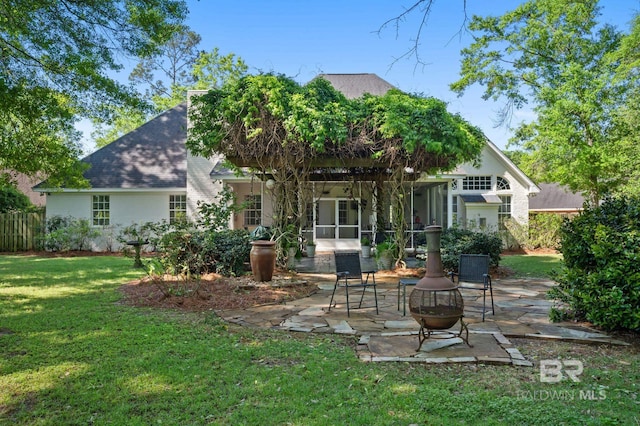 rear view of property featuring a patio, a sunroom, a yard, fence, and a shingled roof