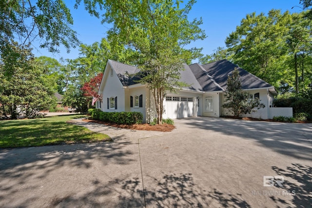 view of front of property with a front yard, an attached garage, driveway, and roof with shingles