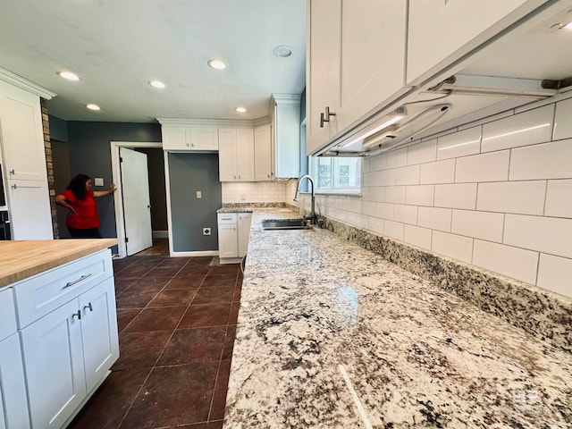 kitchen featuring backsplash, dark tile floors, white cabinets, and sink