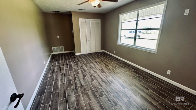 empty room featuring a textured ceiling, ceiling fan, and dark wood-type flooring