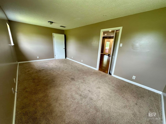 spare room featuring carpet flooring and a textured ceiling