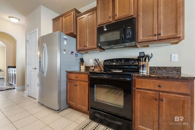 kitchen with dark stone countertops, black appliances, and light tile patterned floors