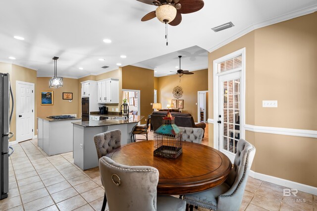 dining space featuring sink, crown molding, light tile patterned flooring, and ceiling fan