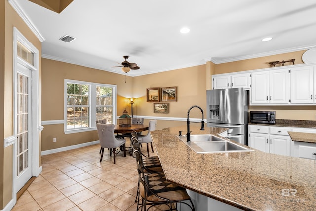 kitchen with a breakfast bar area, stainless steel appliances, ornamental molding, sink, and white cabinets