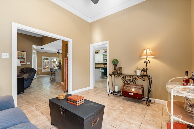 interior space with a towering ceiling, ceiling fan, ornamental molding, and light tile patterned floors