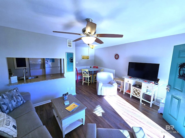 living room with dark hardwood / wood-style flooring, ceiling fan, and sink