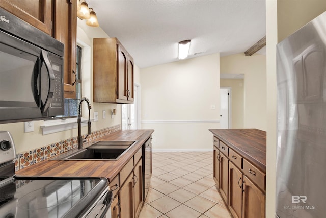 18657 County Road 12, Foley, AL 36535 - kitchen featuring wood counters, stainless steel appliances, a sink, brown cabinetry, and light tile patterned floors