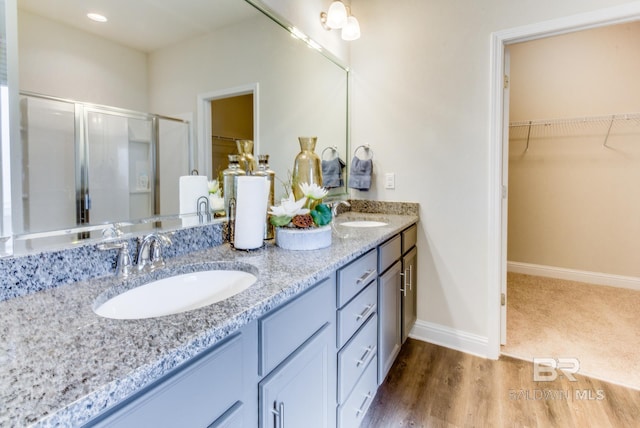 11547 Thistledown Loop, Spanish Fort, AL 36527 - full bathroom with double vanity, a stall shower, a walk in closet, baseboards, and wood finished floors