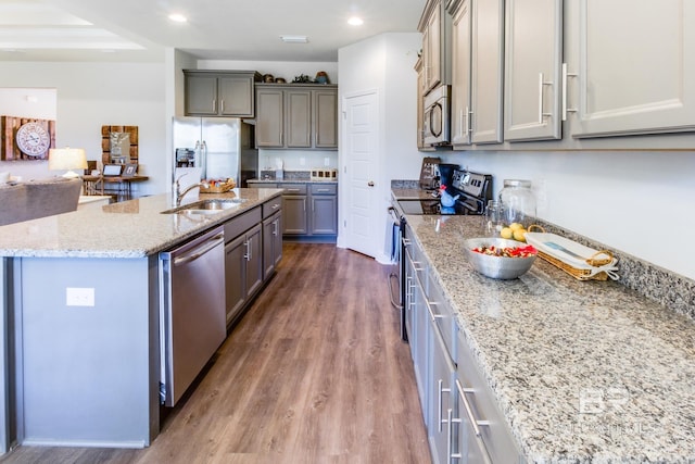 11547 Thistledown Loop, Spanish Fort, AL 36527 - kitchen featuring stainless steel appliances, dark wood finished floors, light stone countertops, a sink, and a kitchen island with sink