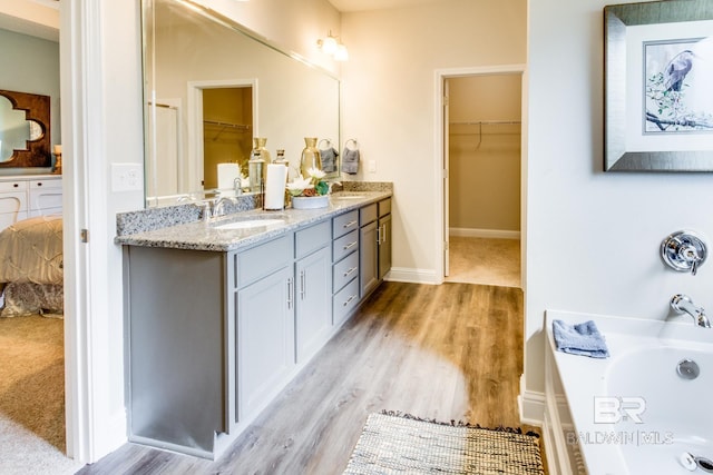 11547 Thistledown Loop, Spanish Fort, AL 36527 - ensuite bathroom with double vanity, a bath, wood finished floors, a walk in closet, and baseboards