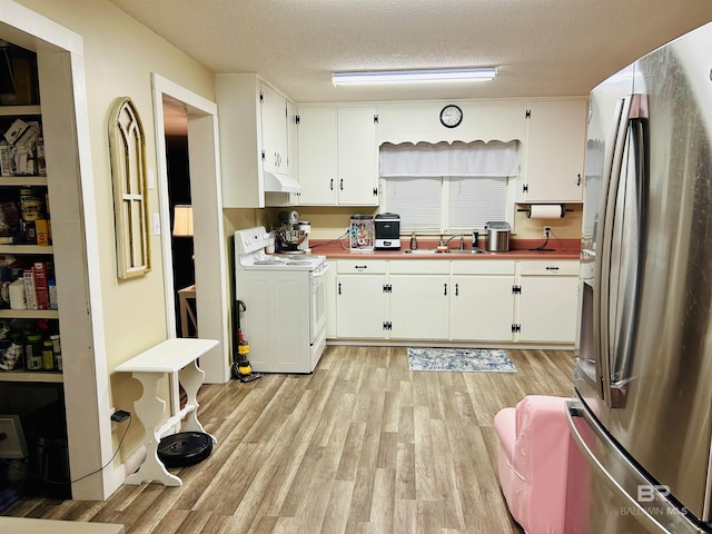 kitchen with stainless steel refrigerator, white range with electric cooktop, a textured ceiling, and white cabinets