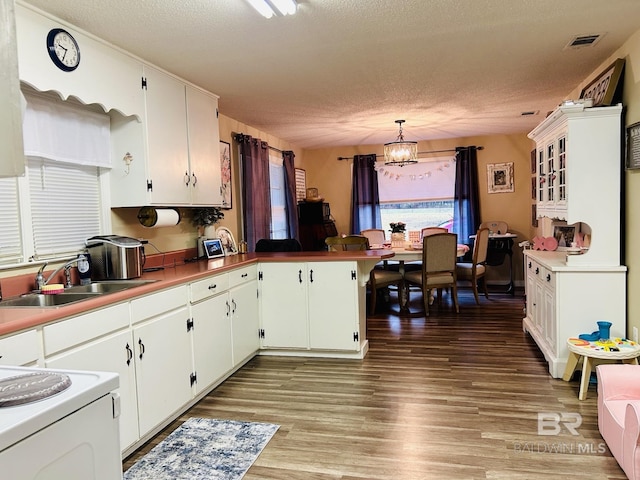 kitchen featuring kitchen peninsula, pendant lighting, sink, white cabinetry, and an inviting chandelier