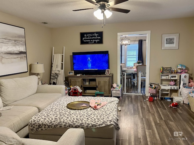 living room with a textured ceiling, ceiling fan with notable chandelier, and dark hardwood / wood-style floors