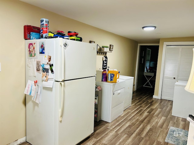 kitchen with washer / dryer, white refrigerator, light wood-type flooring, and white cabinets