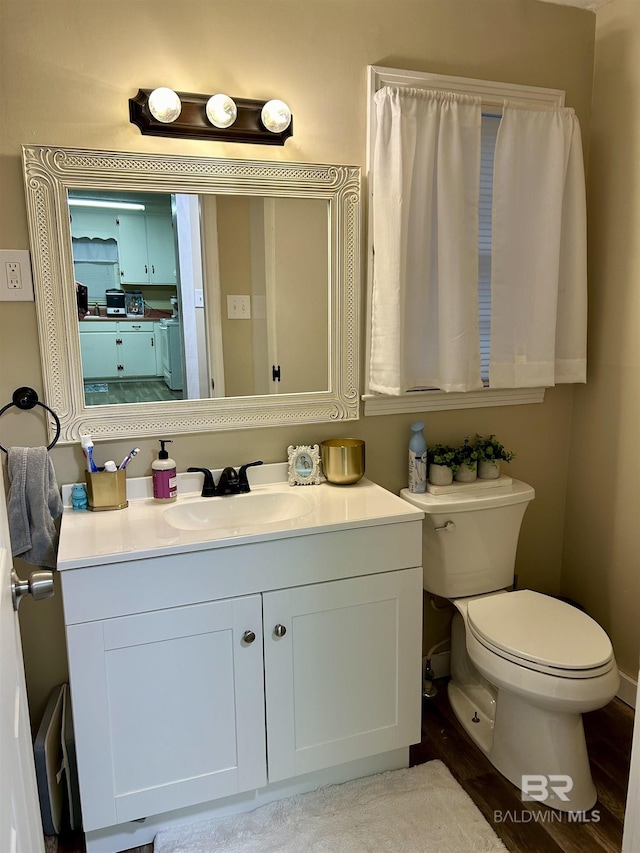 bathroom featuring toilet, wood-type flooring, and vanity