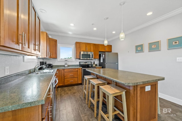 kitchen with appliances with stainless steel finishes, a kitchen island, dark hardwood / wood-style flooring, a kitchen bar, and sink