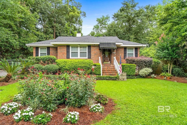 single story home featuring brick siding, a chimney, a front lawn, and roof with shingles