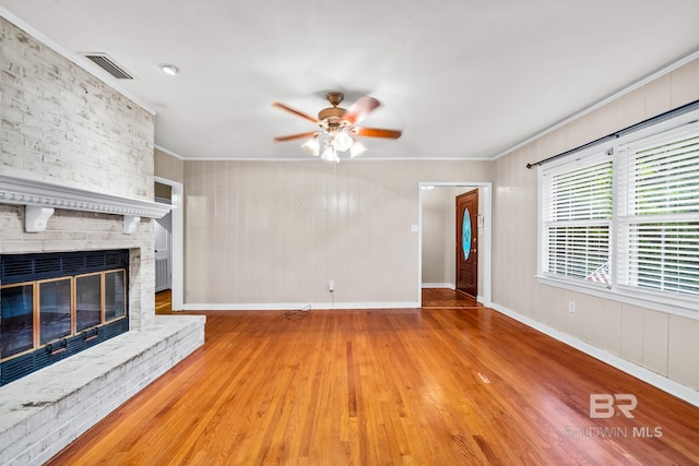 unfurnished living room featuring light hardwood / wood-style floors, a brick fireplace, and crown molding