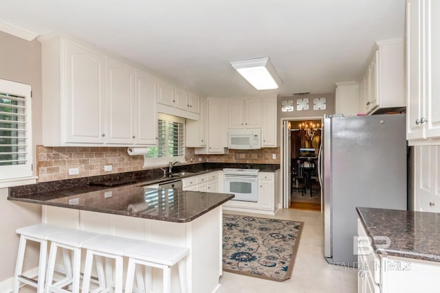 306 Thornton Pl, Mobile, AL 36609 - kitchen featuring white appliances, a peninsula, a sink, decorative backsplash, and dark stone countertops