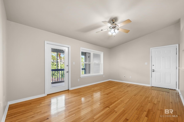 spare room featuring lofted ceiling, light wood-style flooring, and baseboards