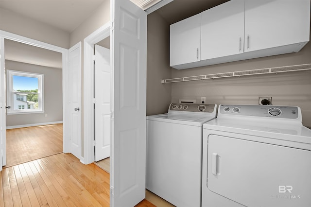 clothes washing area with cabinet space, baseboards, separate washer and dryer, and light wood-style floors