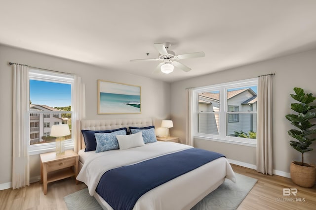 bedroom with light wood-type flooring, ceiling fan, and baseboards