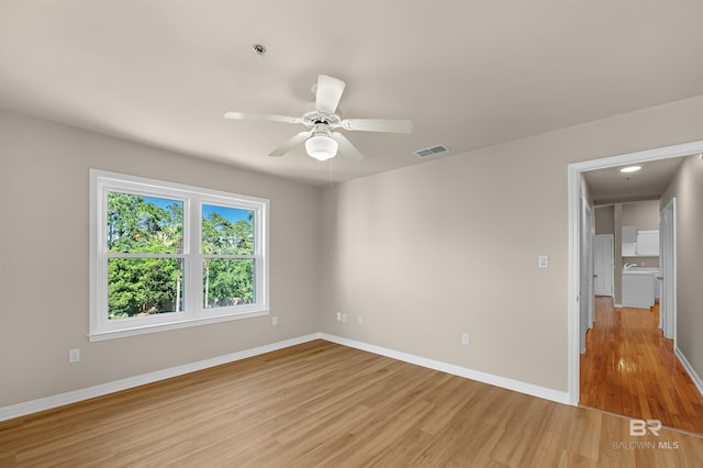 empty room featuring a ceiling fan, baseboards, visible vents, and light wood finished floors