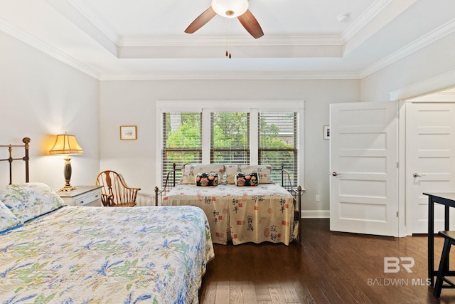 bedroom featuring ceiling fan, crown molding, dark wood-type flooring, and a tray ceiling