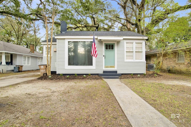 bungalow-style house with entry steps, a chimney, and central air condition unit