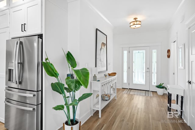 entryway with light wood-type flooring and ornamental molding