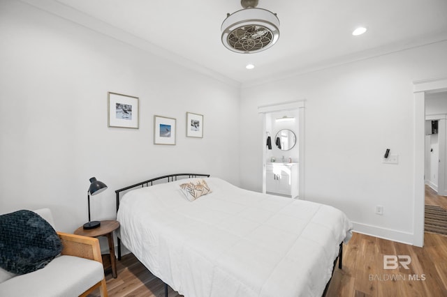 bedroom with hardwood / wood-style floors, crown molding, and connected bathroom