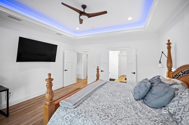 bedroom with a tray ceiling, ceiling fan, crown molding, and hardwood / wood-style flooring