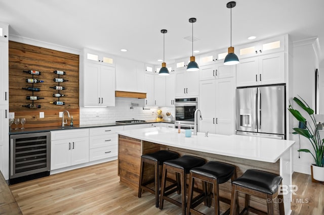 kitchen with appliances with stainless steel finishes, pendant lighting, white cabinets, and wine cooler