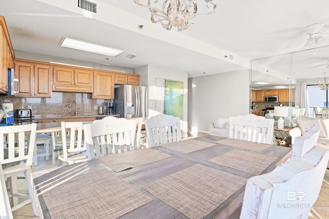 dining area with light tile patterned floors, sink, and a notable chandelier